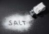 Salt shaker spilling salt on a dark surface