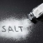 Salt shaker spilling salt on a dark surface
