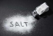 Salt shaker spilling salt on a dark surface