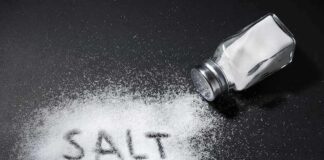 Salt shaker spilling salt on a dark surface