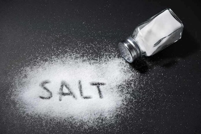 Salt shaker spilling salt on a dark surface