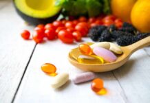 Dietary Supplements: Hype or Help? – Doctors Draw A Line Wooden spoon holding assorted vitamin pills beside fresh fruits and vegetables