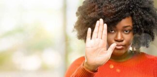 Woman in orange sweater holding up hand in stop gesture