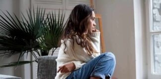 Woman sitting curled up on a chair looking out a window