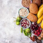 Assorted fruits, grains, bread, and nuts arranged on a gray surface