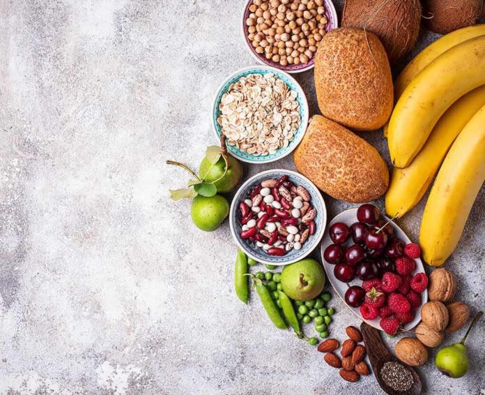 Assorted fruits, grains, bread, and nuts arranged on a gray surface