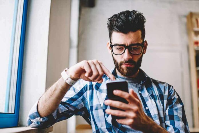 Man using smartphone by a window