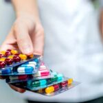 Hand holding blister packs of assorted capsules