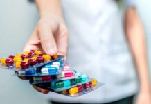 Weight-Loss Meds – Nails Falling Off? Hand holding blister packs of assorted capsules