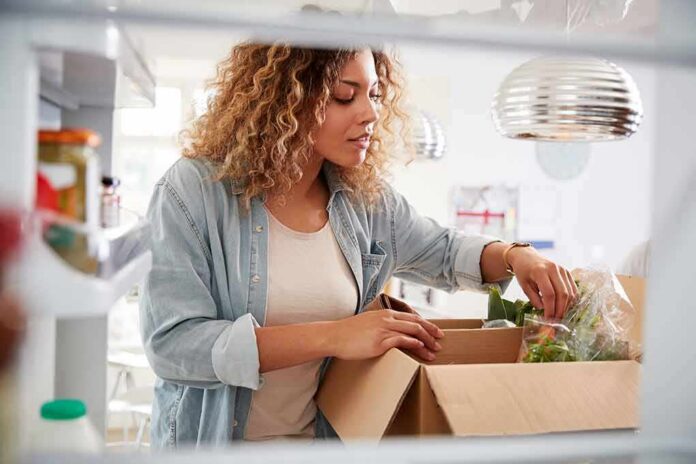 shutterstock_1459827464 Woman unpacking groceries into a refrigerator