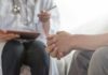 Patient clasping hands during consultation with a doctor