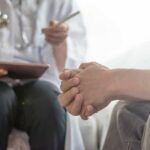 Patient clasping hands during consultation with a doctor