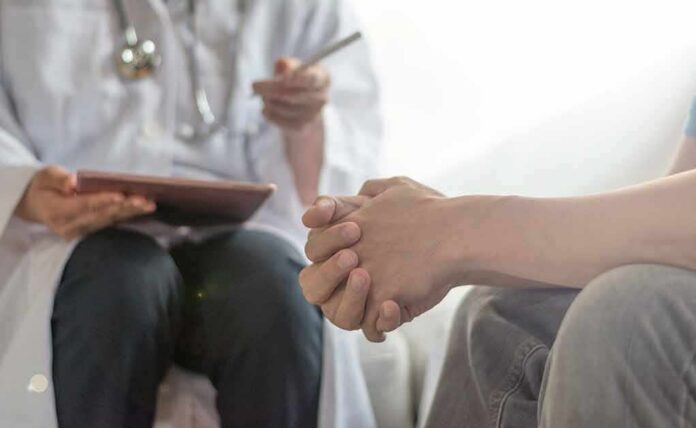 Patient clasping hands during consultation with a doctor