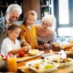 Grandparents and two children cooking together in a bright kitchen