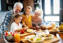 Grandparents and two children cooking together in a bright kitchen