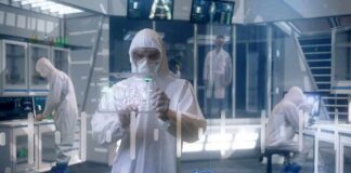 Scientist in hazmat suit using a transparent digital tablet in a lab