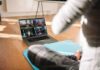 person on yoga mat watching a virtual workout class on a laptop