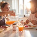Couple eating breakfast with orange juice at a sunlit table