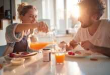 Couple eating breakfast with orange juice at a sunlit table