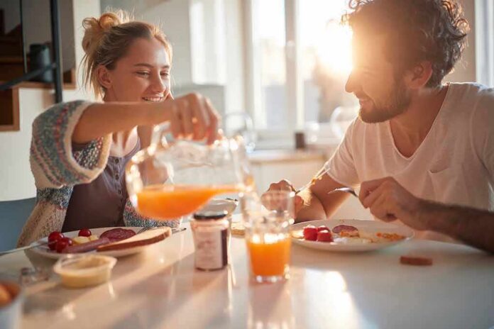 Couple eating breakfast with orange juice at a sunlit table
