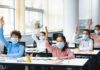 Flu Season Warning: Timelines Matter Schoolchildren wearing masks raise hands in a classroom