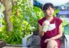 Woman in red dress drinking iced matcha in a garden