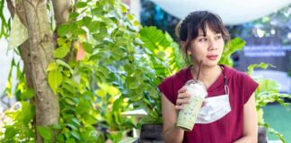 Woman in red dress drinking iced matcha in a garden