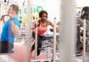 Woman lunging on sled in gym next to man using cable machine