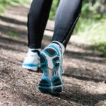 Runner's feet in athletic shoes on a forest trail