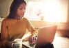Woman working on a laptop with a mug in hand