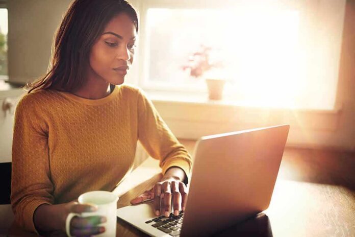 Woman working on a laptop with a mug in hand