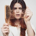 Woman holding a hairbrush with clumps of hair