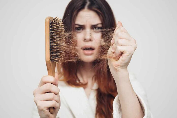 Woman holding a hairbrush with clumps of hair