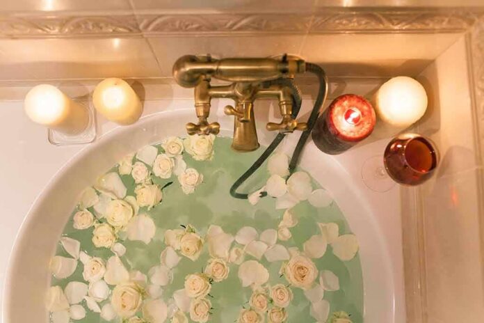 shutterstock_628350224 Bathtub filled with water and white roses under candles