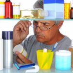 Man reading a pill bottle in a bathroom cabinet